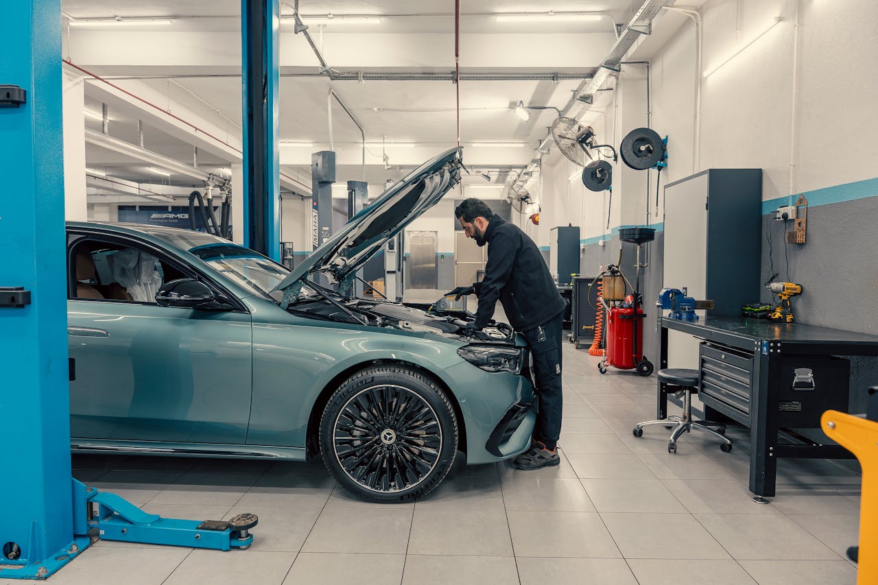 Mechanic inspecting a luxury car inside a well-equipped garage. Vehicle maintenance setting.